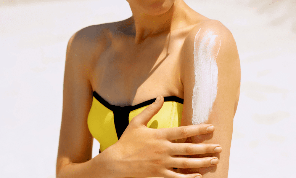 girl in yellow bathing suit applying sunscreen