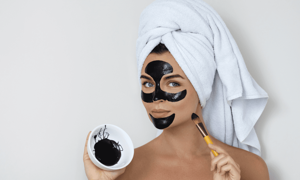 girl applying black mask on her face to remove blackheads