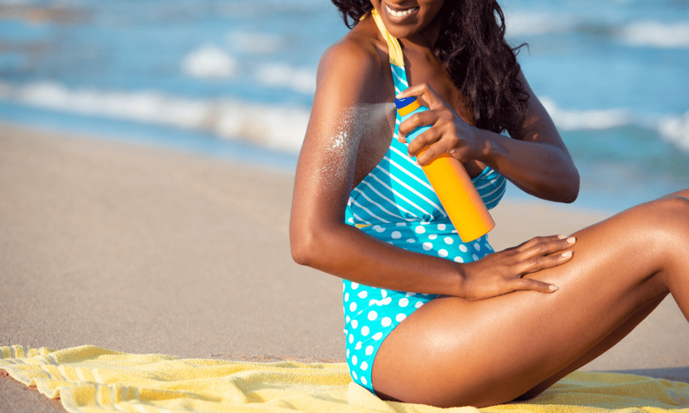 lady applying sunscreen spray on the beach
