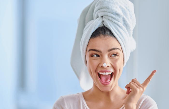lady with white towel on her head moisturizing her face